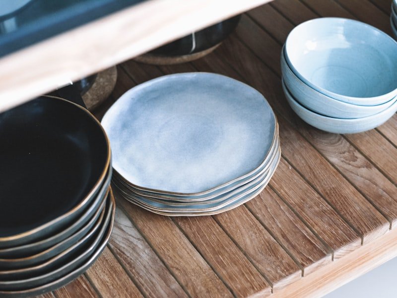 Stacked handmade stoneware plates on a wood bench at the ceramics studio