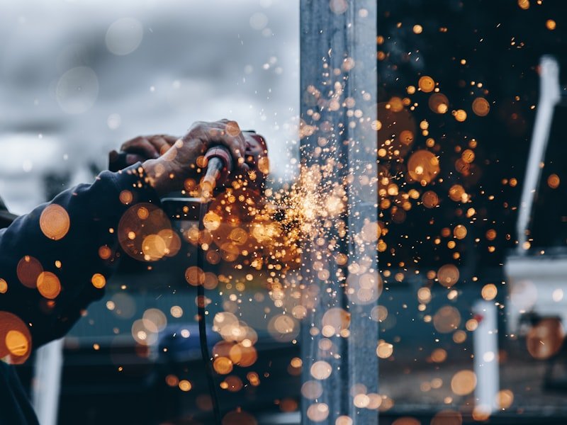 Sparks flying from a hand grinder cutting steel at the metal shop